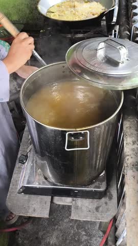 Rich broth bubbling gently in a steel pot on stove, detailed shot crafted for cooking show intros and recipe blogs