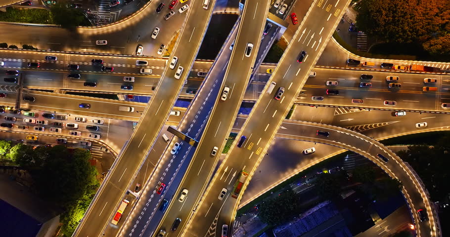 Aerial view of illuminated highway interchange with traffic flow in modern city at night