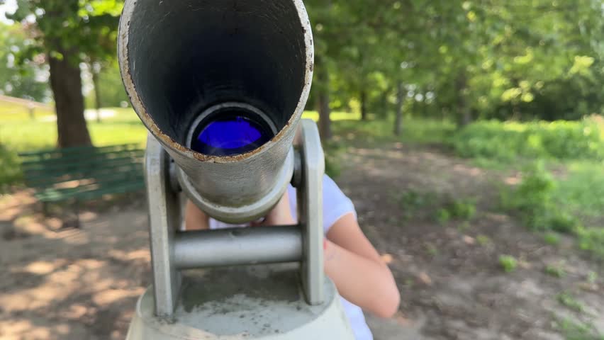 A little girl looks through a telescope on the observation deck. Close-up. Summer walk to the sights. Europe