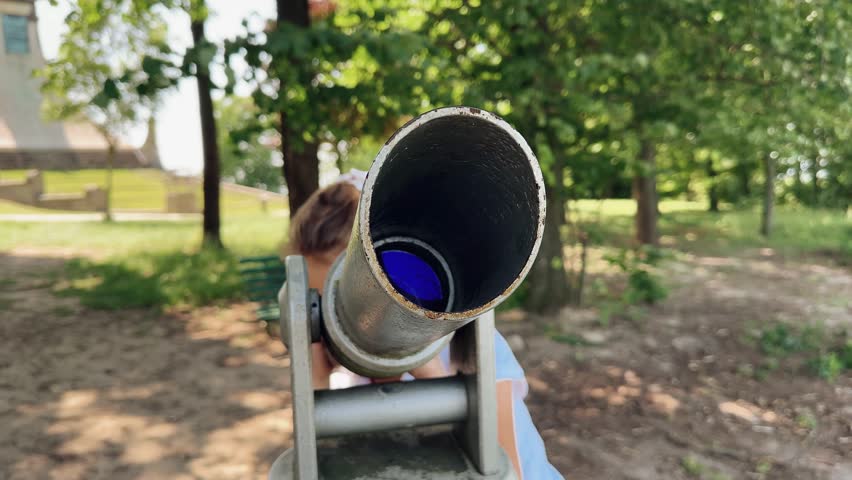 A little girl looks through a telescope on the observation deck. Close-up. Summer walk to the sights. Europe