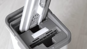 Dip the mop into the bucket for rinsing and wringing. The process of washing a mop in a bucket. Professional mop for home cleaning. Splashing water. A large mop. Close-up. Home cleaning - Powered by Shutterstock - Get 15% off with code: PIKWIZARD15