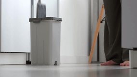 A woman in home clothes is carefully mopping a white floor with a mop. The movement of the mop. Background for cleaning topics, household chores, and cleaning services. - Powered by Shutterstock - Get 15% off with code: PIKWIZARD15