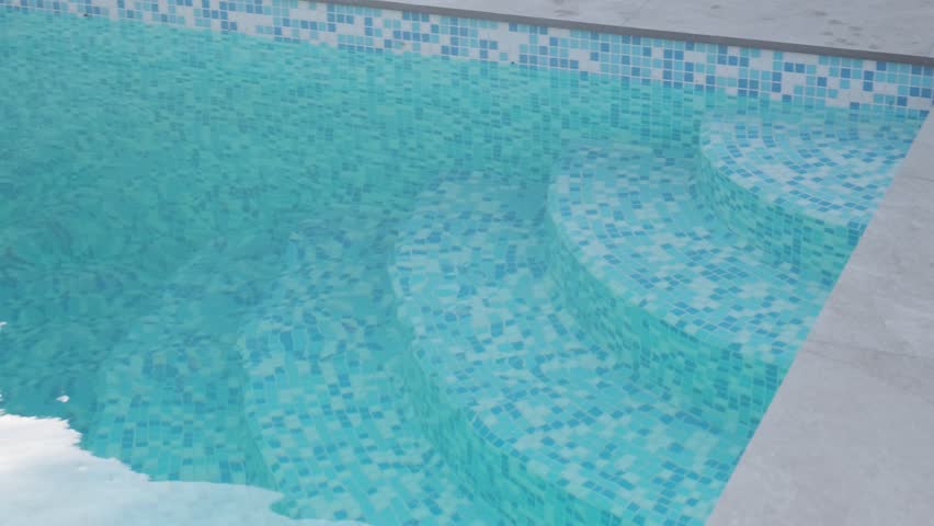 Mosaic steps leading into the water are built into the corner of a swimming pool. Blue tiles and clear water create a clean and refreshing atmosphere
