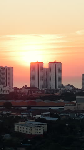 City skyline at sunset with a colorful sky and the ocean in the background