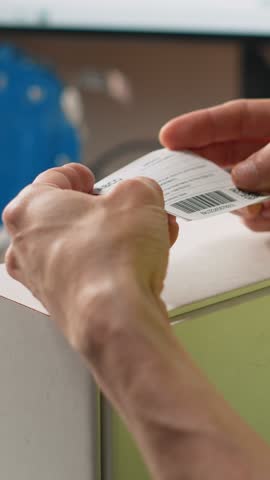 Vertical Video Asian employee applying shipping labels and scanning tracking info, registering the cargo information for parcel status during delivery. Manages labeling tasks with hi vis vest in depot