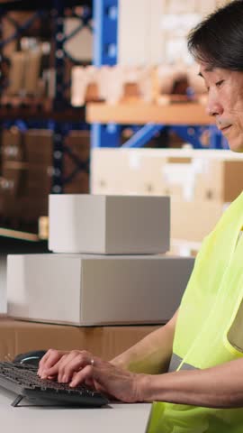 Vertical Video Depot asian worker processing online shopping orders on computer, managing shipment details and awb numbers on professional software. Handles packaging and manages inventory. Camera B.