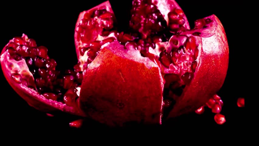 Close-up of a freshly cracked pomegranate fruit with vibrant red seeds scattered on black background, showcasing natural beauty, texture, and rich color contrast in slow motion, 4k 60fps.