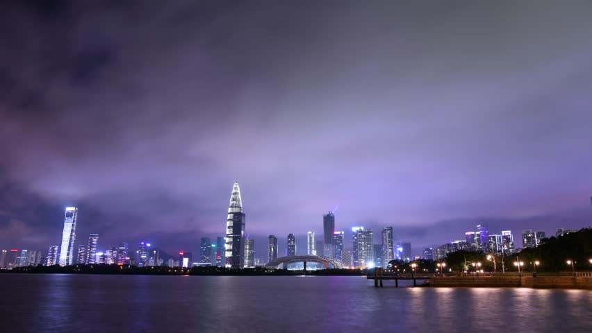 Experience the dynamic beauty of Shenzhen Bay as the vibrant city skyline lights up against a tranquil water backdrop during the night. Watch the transformation unfold.