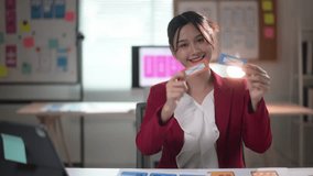 Young woman designer is sitting at her desk comparing two different color swatches for a project - Powered by Shutterstock - Get 15% off with code: PIKWIZARD15