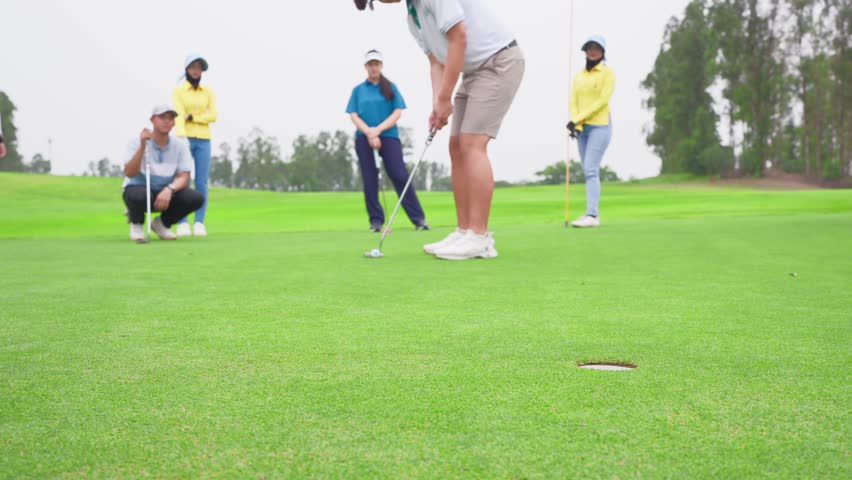 Close up of young pro golfers swings their club on scenic golf course. Attractive athletes enjoy outdoor recreation with light exercise and sport lifestyle while playing golf at course ground together