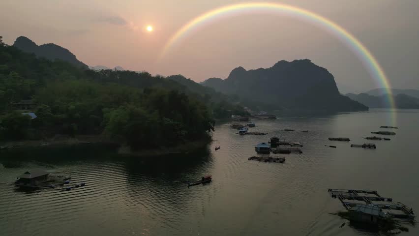A stunning rainbow arches across the sky after rainfall, captured from a drone over the sea near the bay.