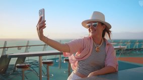 A joyful woman enjoys a beautiful sunset cruise, capturing playful selfies against the stunning ocean backdrop. These moments at sea are perfect for fun, relaxation, and creating lasting memories - Powered by Shutterstock - Get 15% off with code: PIKWIZARD15