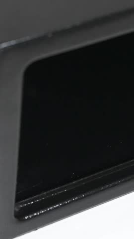 Vertical Close up of a man hand put a stack of one hundred dollar bills into a black steel digital safe box and locking the door. Guarantee of the safety of your savings