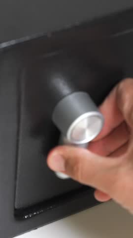 Vertical Close up of a man hand put a stack of one hundred dollar bills into a black steel digital safe box and locking the door. Guarantee of the safety of your savings