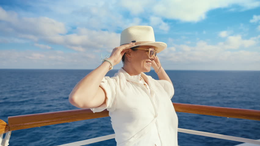 A stylish woman revels in the refreshing ocean breeze while aboard a stunning cruise ship, capturing her carefree days by the beautiful seaideal for lovers of travel and seekers of sunshine