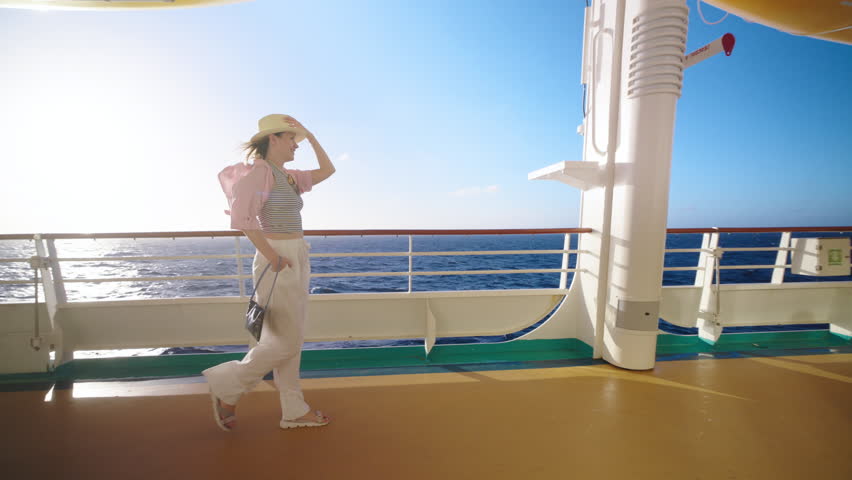 A stylish woman elegantly strolls the sunlit deck of a truly magnificent cruise ship, savoring the breathtaking ocean view and delightful weather that accompanies this splendid, unforgettable day