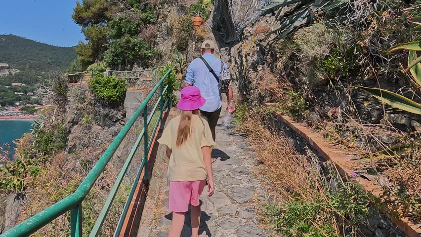 Cinque Terre, Italy - June 25, 2025. Teenage girl with father along mountainside near sea on path. Summer in Liguria, Italy. 