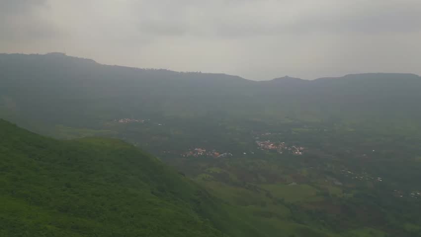 A drone shot captures the lush green mountains of Panchgani, Maharashtra, draped in monsoon mist, with glimpses of the hill city nestled among the clouds, creating a serene and dreamy landscape