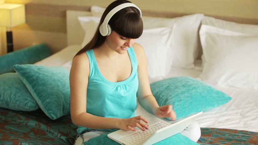 Teenager typing at notebook and listening music
