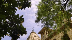 4K tilt-up video of Kirti Mandir temple in Vadodara, Gujarat, India. The shot showcases ornate heritage architecture against partly cloudy sky, framed by lush green trees. - Powered by Shutterstock - Get 15% off with code: PIKWIZARD15