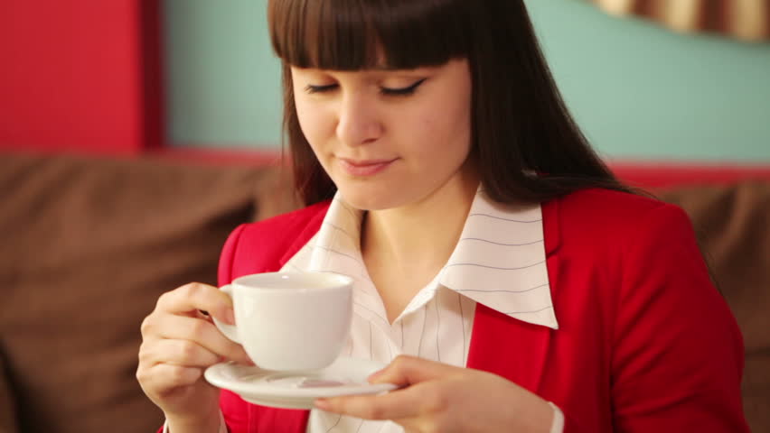 Woman drinking coffee and laughing at camera
