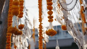 Close-up of marigold garlands and white feathers hanging in sunlight. Perfect for cultural events, festivals, wedding decor, spirituality, and traditional ceremonies. - Powered by Shutterstock - Get 15% off with code: PIKWIZARD15