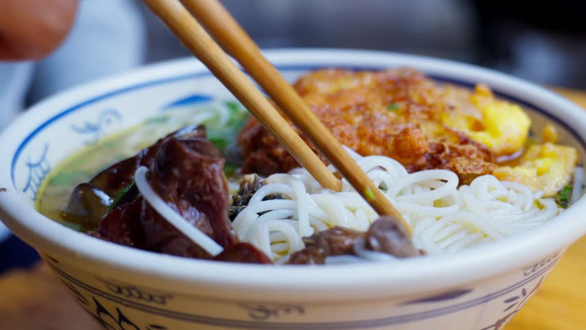 A bowl of Yunnan-style rice noodles topped with native chicken slices in clear broth—highlighting savory warmth, regional texture, and the wholesome charm of ethnic Chinese street cuisine.