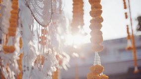 Close-up of marigold garlands and white feathers hanging in sunlight. Perfect for cultural events, festivals, wedding decor, spirituality, and traditional ceremonies. - Powered by Shutterstock - Get 15% off with code: PIKWIZARD15