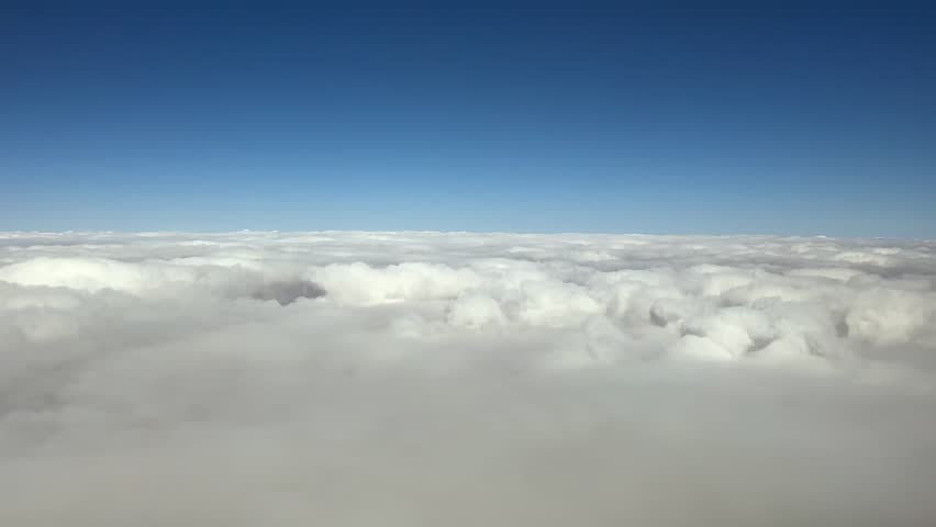 POV flying through an endless thin layer of stratus clouds through the pilot’s eyes from inside a jet cockpit flying at supersonic speed.