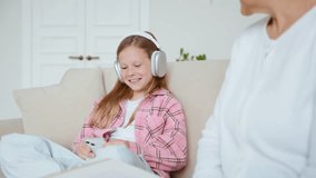 While the granddaughter wears headphones and looks at her smartphone, the grandmother reads a book aloud, trying to spark interest. A striking scene of generational divide in the digital age. 4k - Powered by Shutterstock - Get 15% off with code: PIKWIZARD15