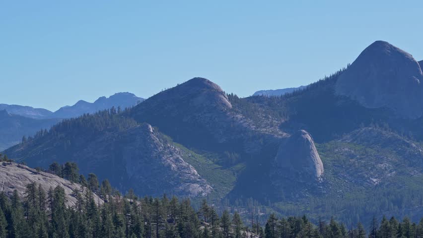 Footage featuring a zoomed pan view of the granite landscape of Yosemite National Park in California, USA. The shot highlights the rugged rock formations and natural beauty of this national park