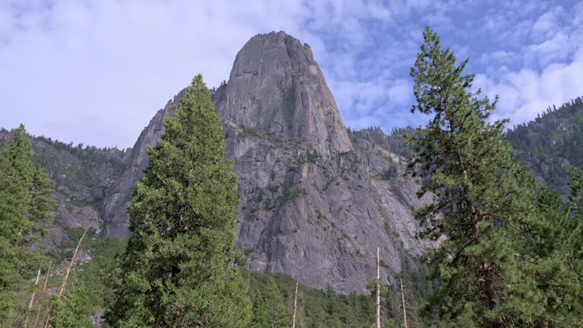 Footage showing clouds slowly passing over massive granite rock formations in Yosemite National Park, California.