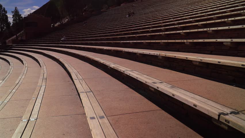 Red Rocks Park and Amphitheater band music staircase stage Morrison Colorado aerial drone mid winter sunny blue sky clouds tourist destination large sandstone feature forward pan up motion