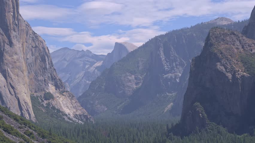 Footage showing a static shot of clouds drifting over Half Dome, the iconic granite formation in Yosemite National Park, California