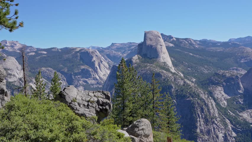 Footage showing a panoramic pan from Glacier Point in Yosemite National Park, California. The scene features breathtaking views of Yosemite Valley, including Nevada Falls and Vernal Falls.