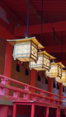 Illuminated lanterns hang inside a vibrant red Japanese shrine, showcasing intricate details and traditional architecture. The serene atmosphere evokes a sense of peace and cultural richness.