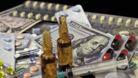 Pills, Ampoule Medications, Syringes and US Dollar Bills Rotate on Black Background - Video Montage. 100 US dollar bills on a pile of medical pills, tablets, ampoules on a black background. - Powered by Shutterstock - Get 15% off with code: PIKWIZARD15