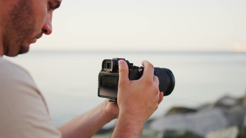 Young photographer capturing sunset moments by the sea with a DSLR camera