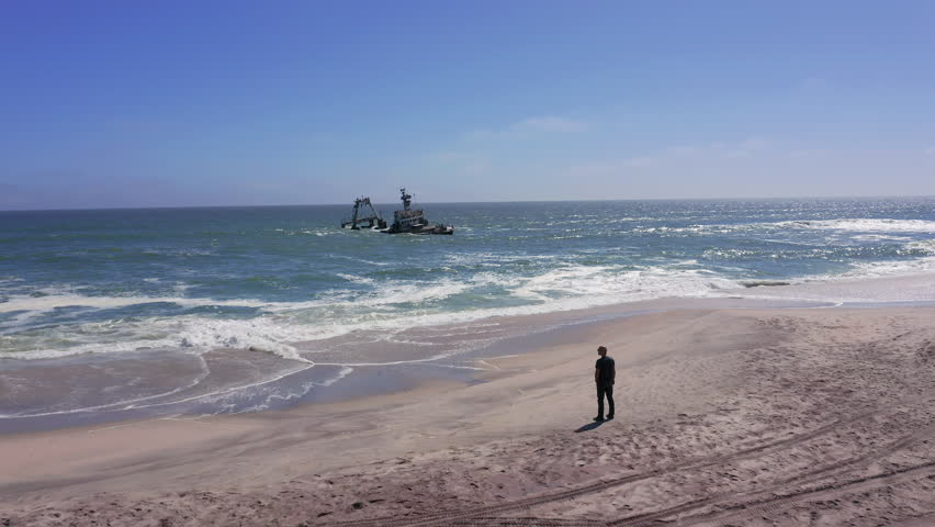 A single person stands quietly before the wrecked Zeila shipwreck in Skeleton Coast, Namibia