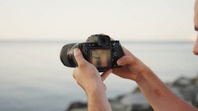 Young photographer capturing the sunset by the sea, holding a DSLR camera - Powered by Shutterstock - Get 15% off with code: PIKWIZARD15