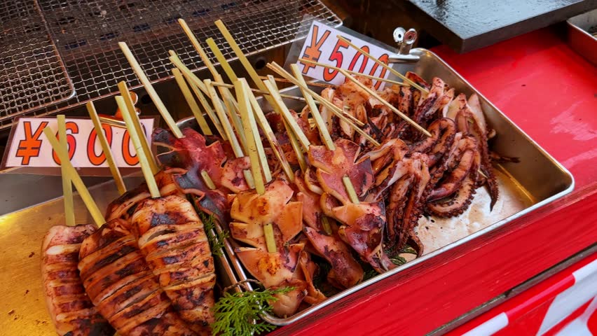 Delicious Japanese street food: yakitori skewers (¥500) and Takoyaki (¥600) displayed at a vibrant food stall. A tempting culinary experience!