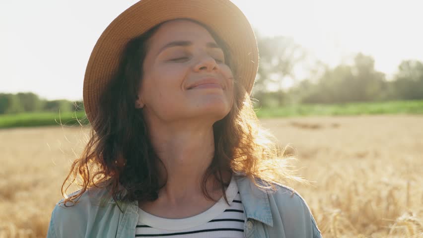 Portrait of a young Caucasian woman in a straw hat against the background of a rye field