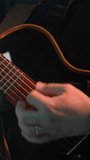 Faceless guitarist in a black shirt playing guitar against a grey background. The close-up captures the intricate details of the guitar and the musician's hands - Powered by Shutterstock - Get 15% off with code: PIKWIZARD15