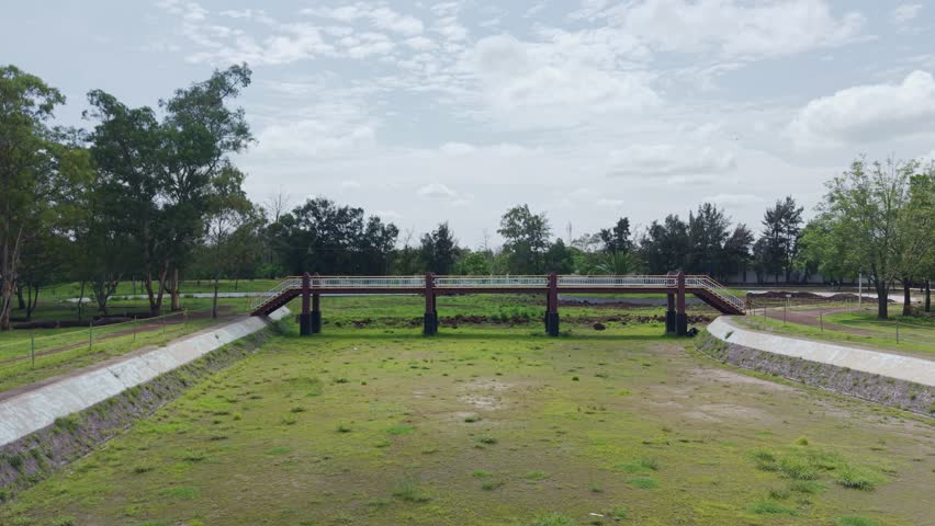 Drone view passing under a bridge in a park