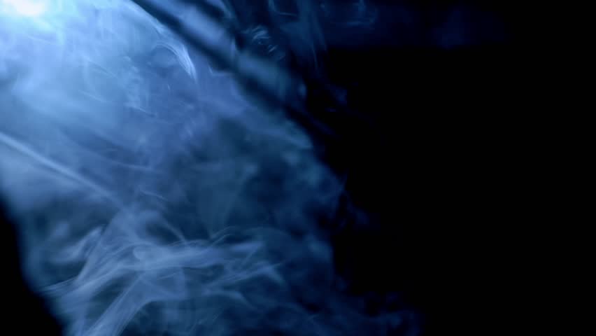 Abstract image of soft blue smoke swirling gently against a dark background, creating a mysterious and atmospheric visual effect.