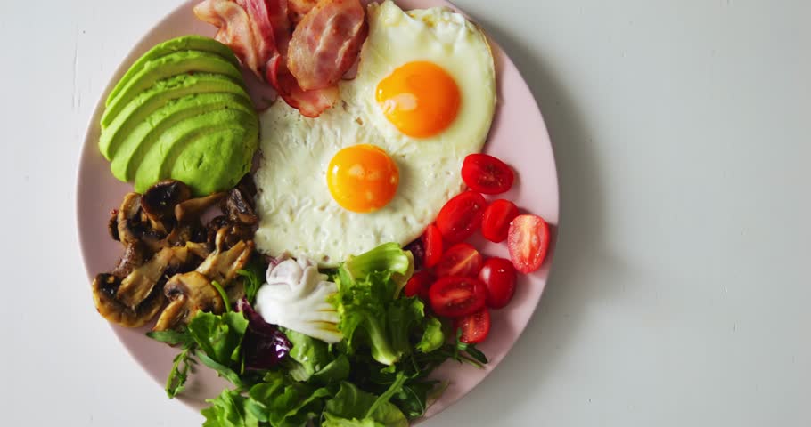 Fresh and healthy ingredients for special keto breakfast lie on thin plate. Scrambled eggs with vegetables and bacon allow person to adhere to low-carb diet