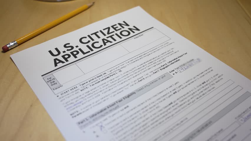 Close-up of a U.S. citizenship application form stamped “APPROVED” in bold red letters. A pencil rests on the desk beside the document, symbolizing success in the naturalization process. 14707  	