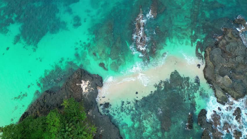 Descending in a spiral over the transparent sea with the waves breaking and crossing each other. Boi beach, Ilha do Principe (Prince Island) São Tomé,Africa