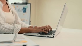 Businesswoman typing on a laptop at a modern white desk with charts and graphs in the background - Powered by Shutterstock - Get 15% off with code: PIKWIZARD15