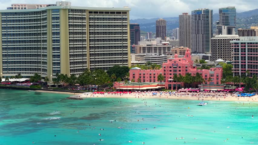 The pink Royal Hawaiian Hotel on a crowded Waikiki beach, aerial view